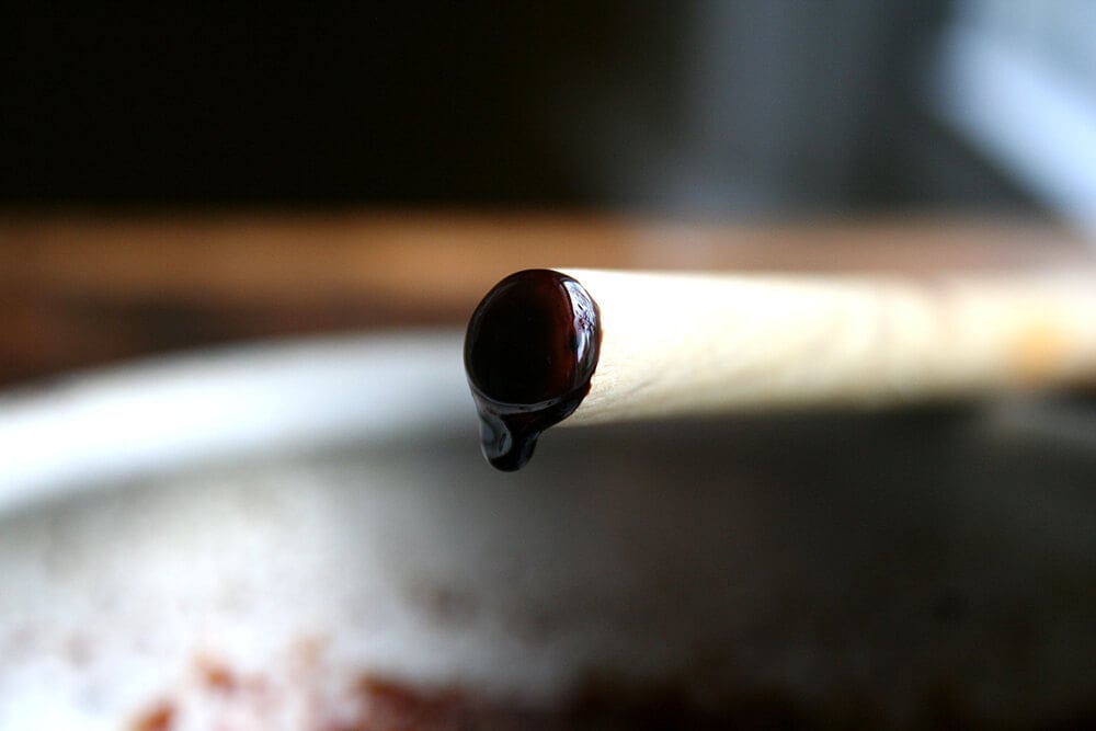 Close-up of syrupy balsamic dripping off butt-end of wooden spoon