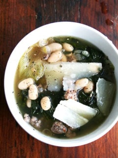 A bowl of white bean and escarole and sausage soup.