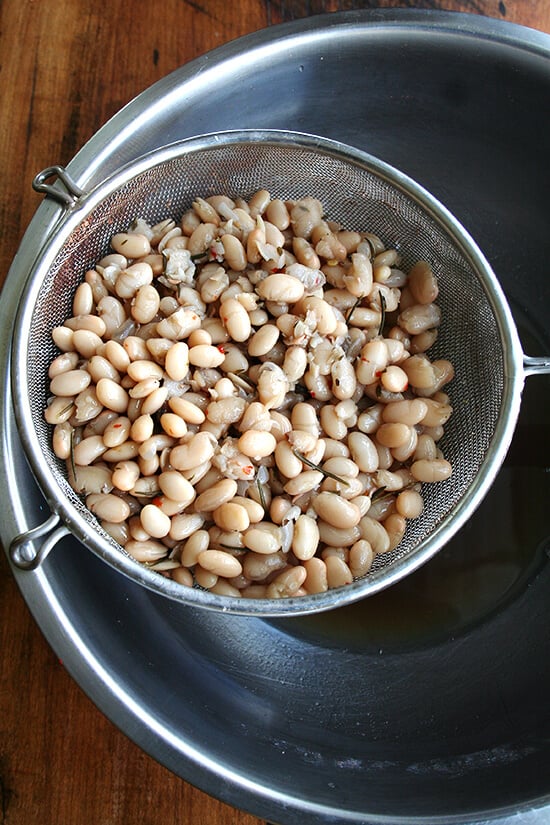 A strainer holding cooked white beans.