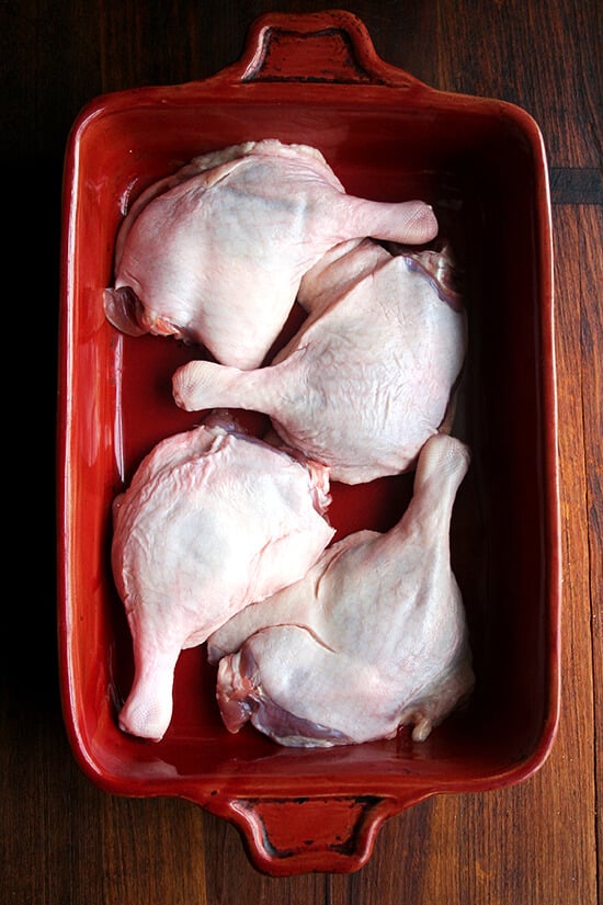 Four duck legs in a 9x13-inch red baking dish. 