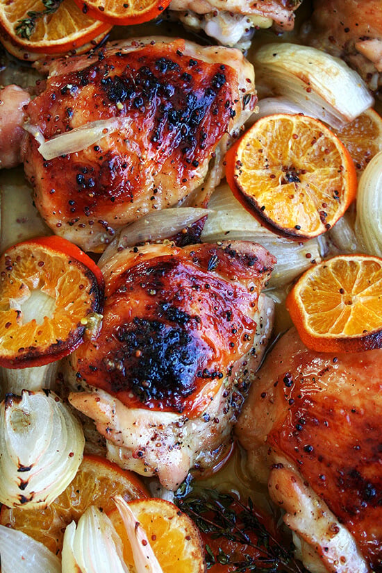 An up close shot of roast chicken and clementines. 