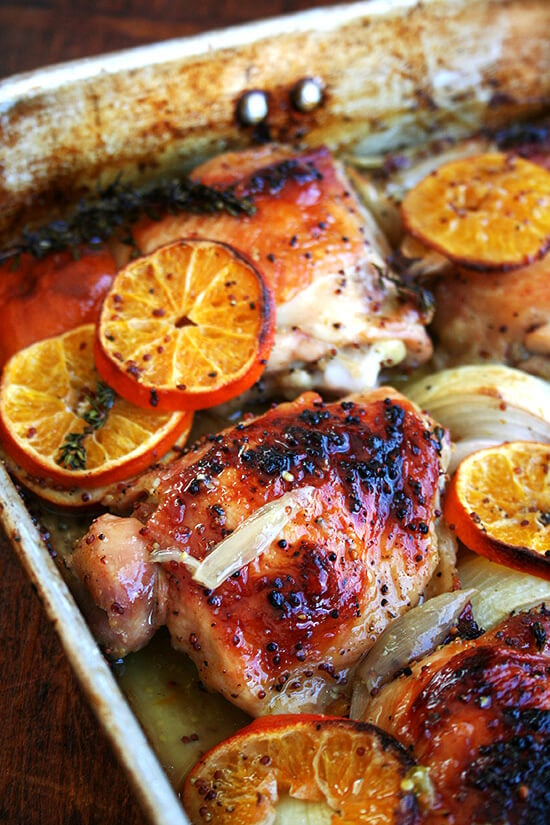 A roasting pan with roast chicken and clementines.