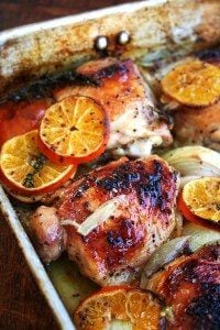 A roasting pan with roast chicken and clementines.