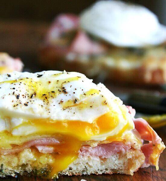 Croque madame — croque monsieur topped with a poached egg — on a cutting board.