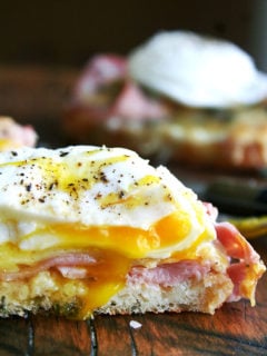 Croque madame — croque monsieur topped with a poached egg — on a cutting board.