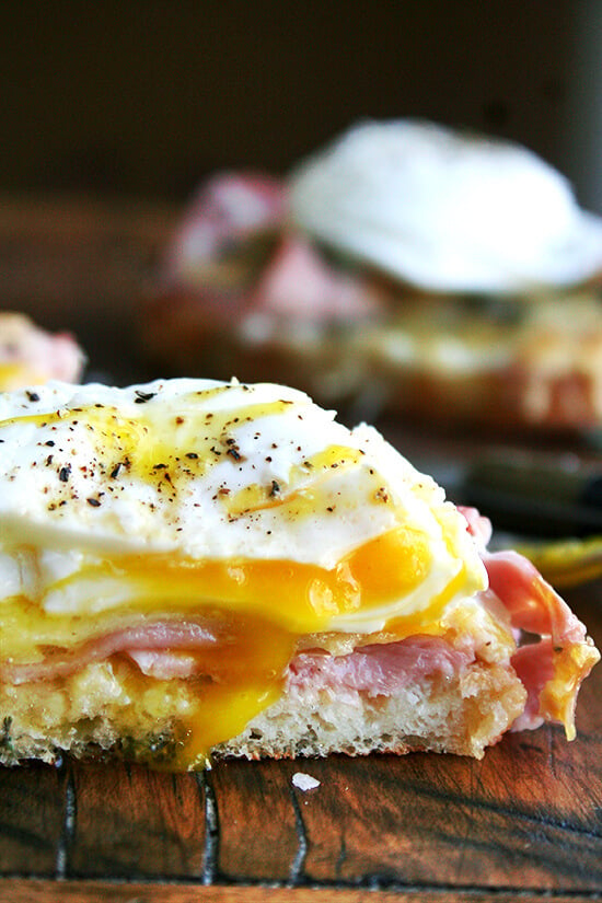 Croque madame — croque monsieur topped with a poached egg — on a cutting board.