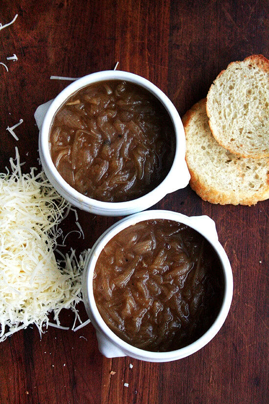 Two bowls of French onion soup, ready for their bread and cheese topping. 