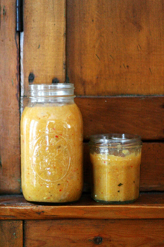 Two jars of preserved lemon purée standing on a shelf. 