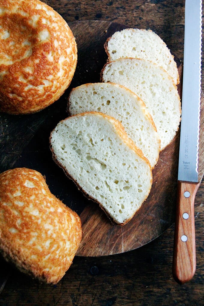 A sliced loaf of gluten-free peasant bread on a board.