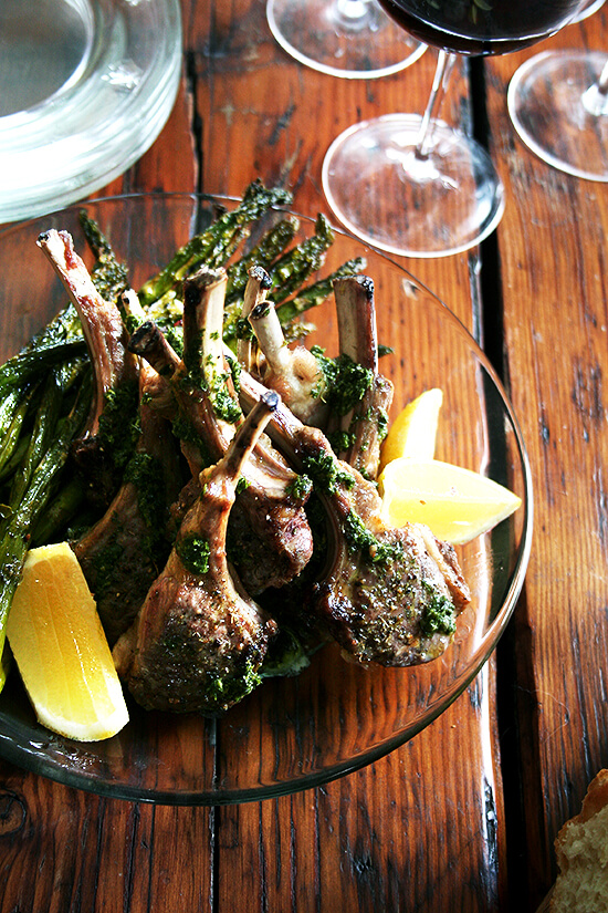 A platter of broiled lamb chops drizzled with mint sauce.