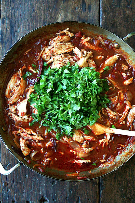 A skillet filled with tinga and cilantro.