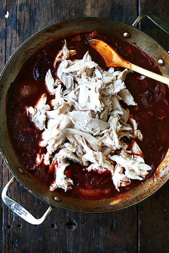 A skillet with onions, chipotles, and shredded chicken.