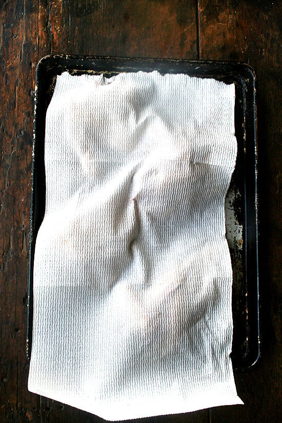 drying off chicken on a sheet pan with paper towels