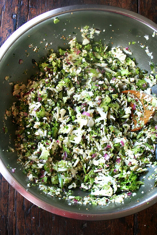 A large bowl of broccoli - cauliflower salad all tossed together. 