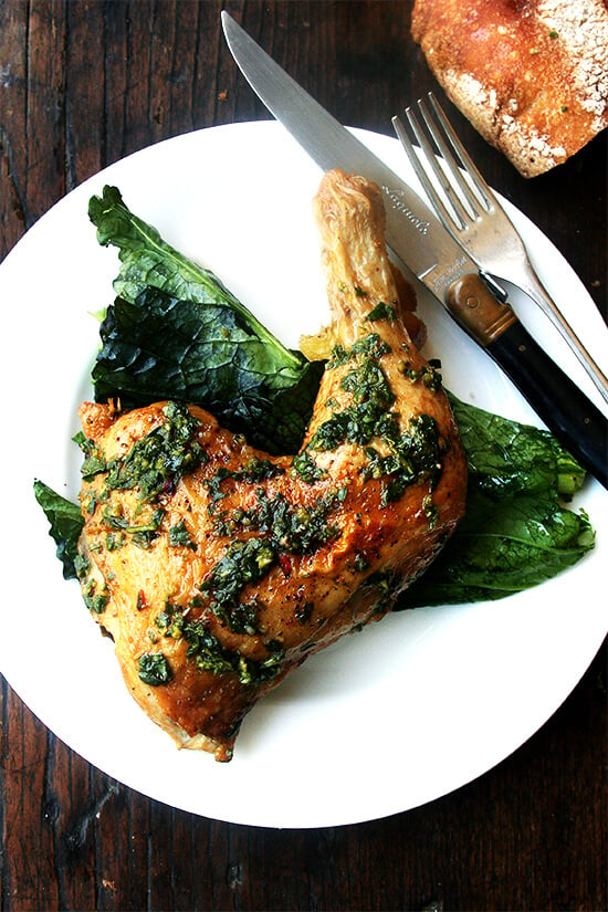 A plate of crispy, herby roasted chicken on top of mustard greens. 