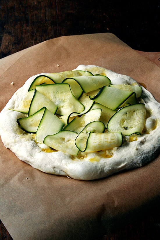 A round of pizza dough topped with zucchini ribbons.