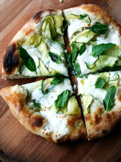 A zucchini, burrata, and anchovy pizza topped with fresh basil.