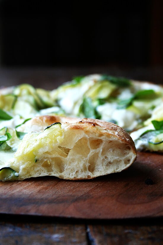 A sideview of a piece of zucchini-anchovy pizza. 