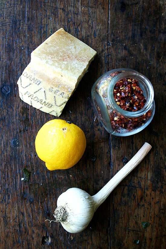 Parmesan, lemon, garlic and pepper flakes on a board. 
