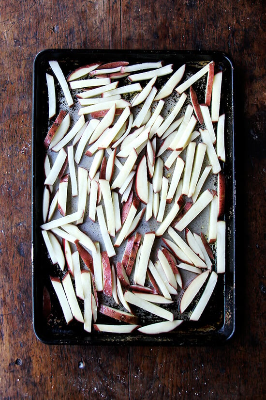 A sheet pan of cut potatoes ready for the oven.