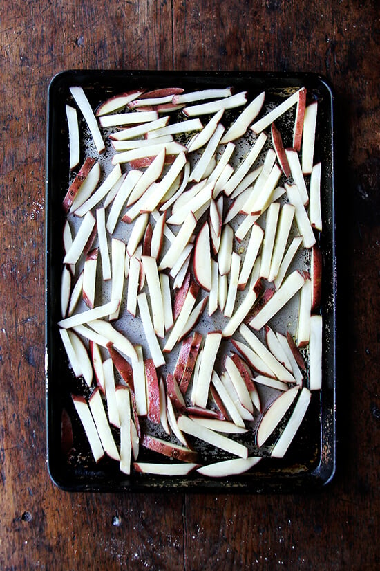 een pan met in stukken gesneden aardappelen klaar voor de oven.