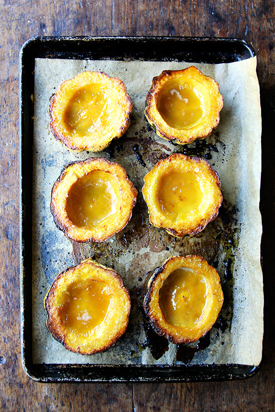 Six acorn squash halves roasted with maple butter on a sheet pan. 