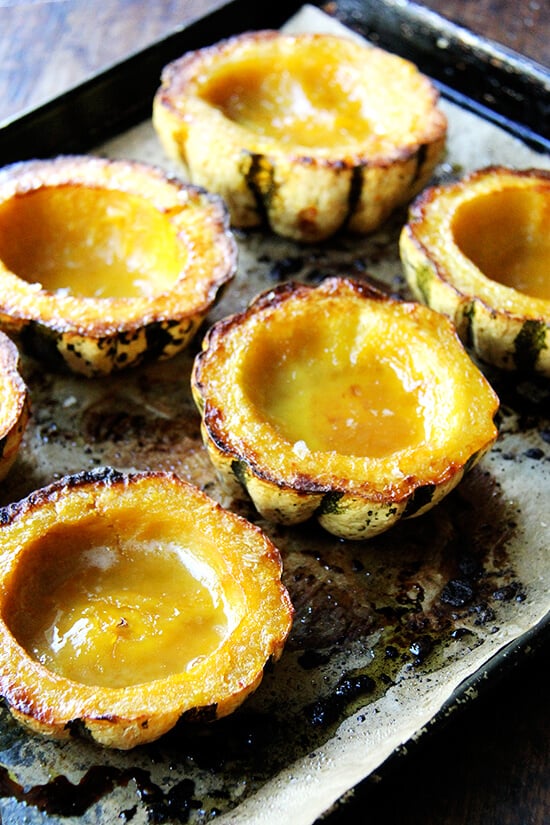 A sheet pan with 6 acorn squash halves roasted with maple butter. 