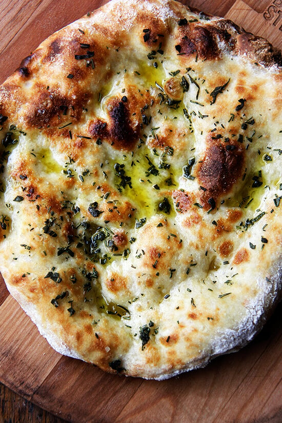 Just-baked herbed flat bread on a board.