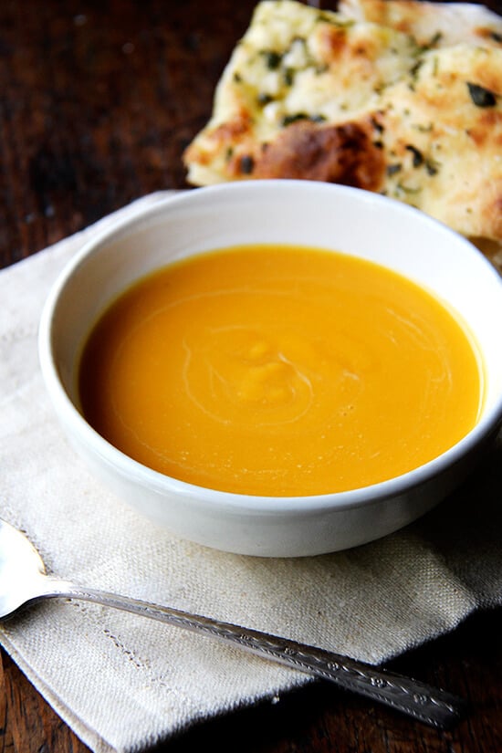 A bowl of butternut squash and cider soup with a spoon. 