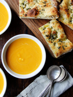 Bowls of butternut squash and cider soup aside herbed flatbreads.