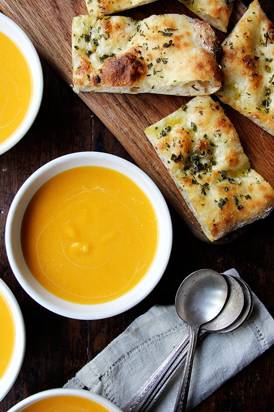 Bowls of butternut squash and cider soup aside herbed flatbreads.