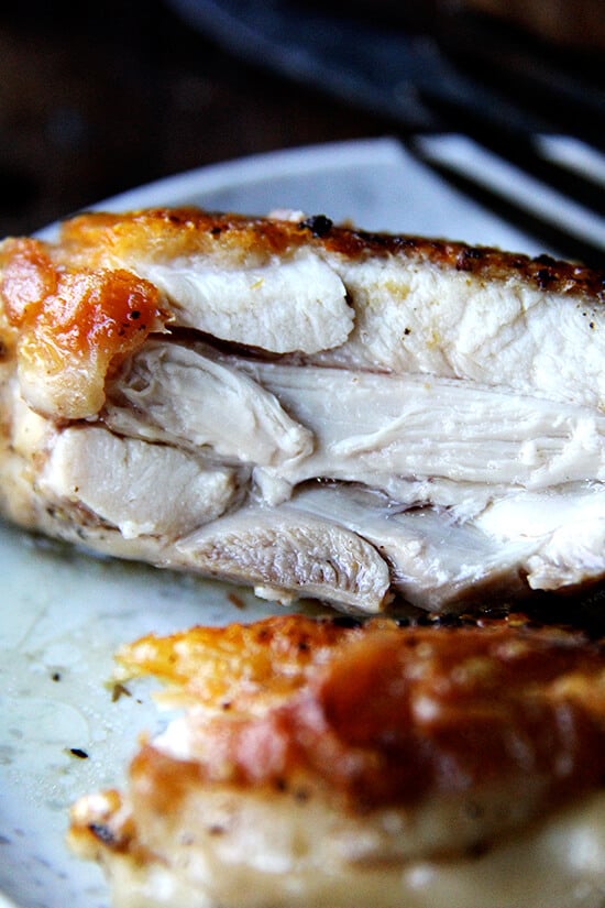 A chicken thigh on a plate cut in half.