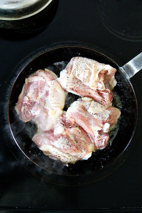 An overhead shot of chicken thighs in a skillet stovetop.