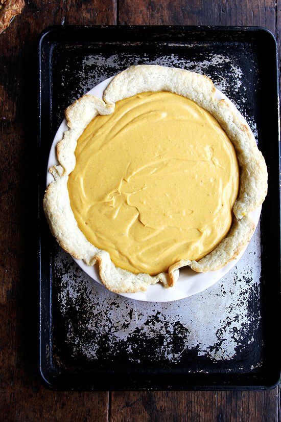 Squash pie unbaked on a rimmed sheet pan. 
