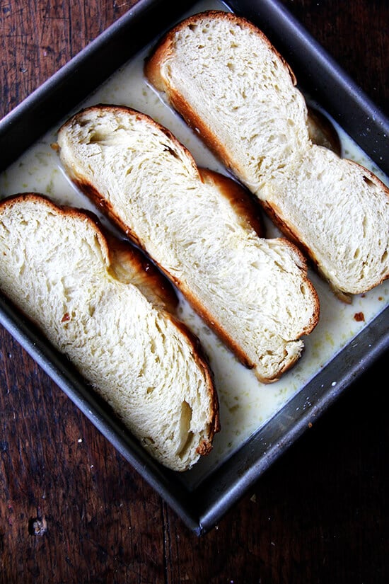 Soaking challah bread in custard in preparation for French toast.