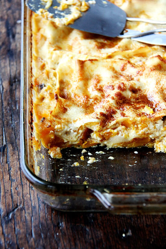 A butternut squash lasagna, freshly baked, with one slice removed from the pan. 