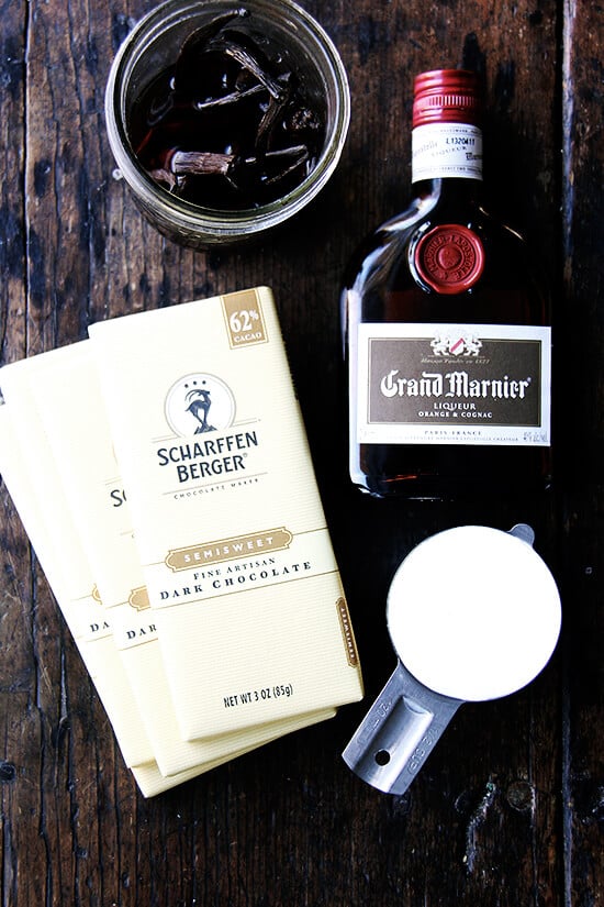 Ingredients for boozy chocolate truffles on a table: chocolate bars, cream, vanilla beans, and Grand Marnier.