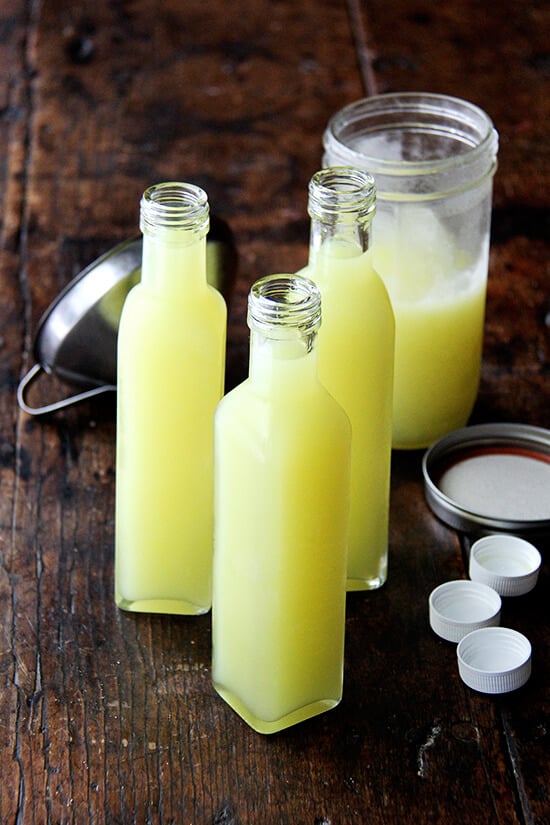 Tall, narrow glass bottles filled with homemade limoncello. 