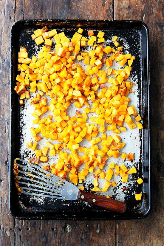 A rimmed sheet pan filled with roasted butternut squash cubes.