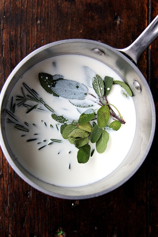A sauce pan filled with milk, sage and rosemary.