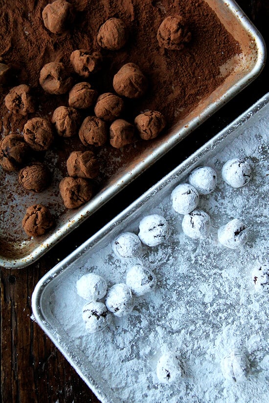 Two sheet pans with truffles: one covered with powdered sugar; the other covered with cocoa powder.