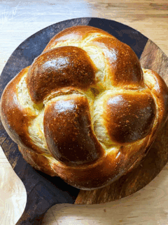 A loaf of challah on a circular cutting board.