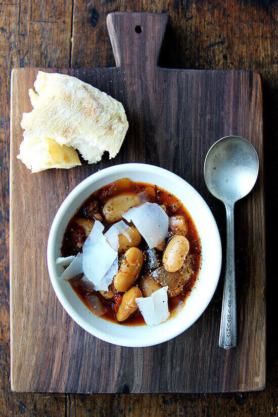 A bowl of slow cooker large white beans (gigante beans) aside a hunk of bread.