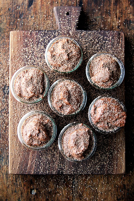 An overhead shot of jars filled with chocolate mousse and topped with chocolate shavings.