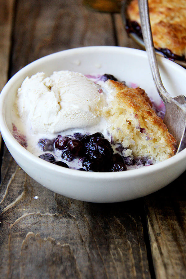 A close-up shot of a bowl of blueberry cobbler with ice cream.