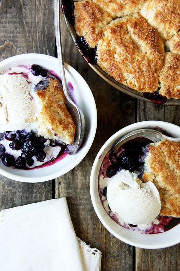 Bowls of blueberry cobbler with ice cream on a table.