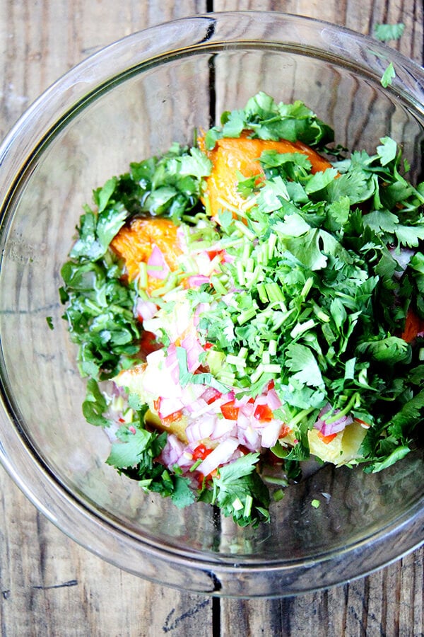 adding the cilantro, chilies, shallots, and lime to the sweet potatoes in a bowl