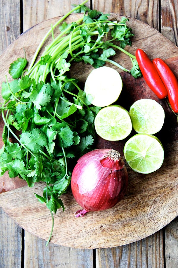 limes, cilantro, onion, chilies on a board.