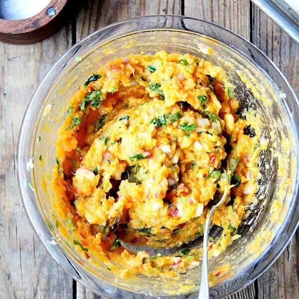 A bowl of mashed sweet potatoes, with chilies, lime, and cilantro.