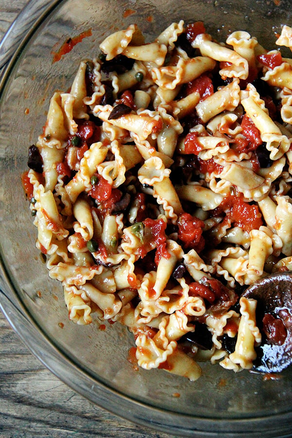 A bowl of pasta tossed with puttanesca sauce. 